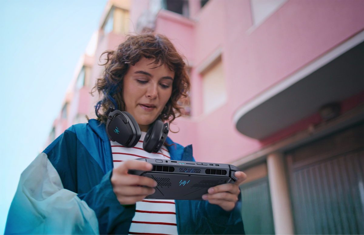 A person wearing headphones holding the Acer Predator Atlas 8 outdoors