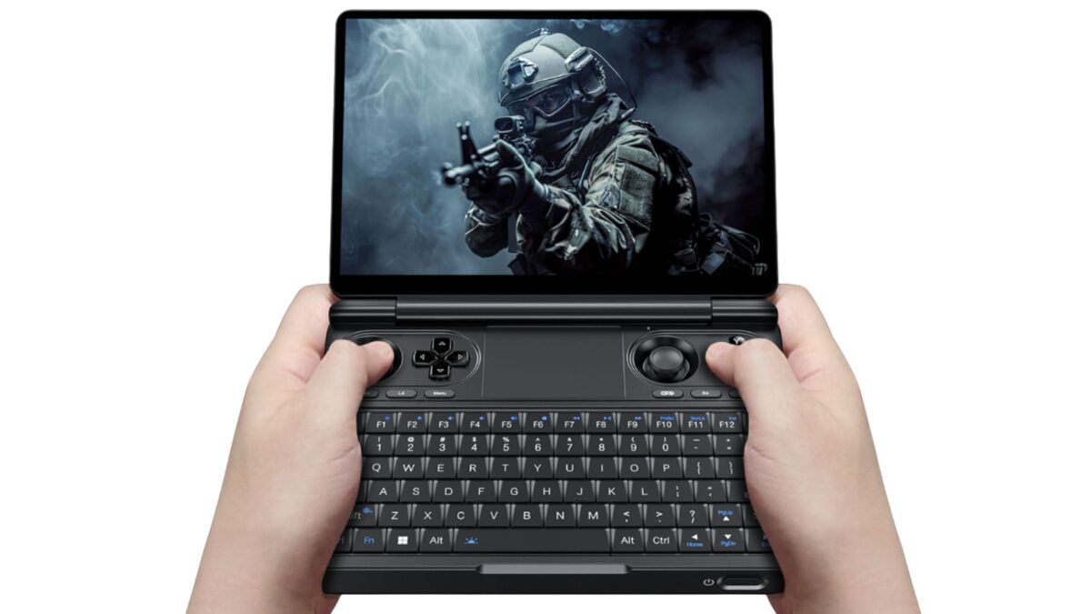 Hands holding the GPD WIN Mini Ultra with its screen open above the keyboard and controls